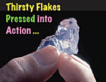 Photo of fingers holding a piece of Super Slurper  with the text: 'Thirsty Flakes Press into Action' Link to story.